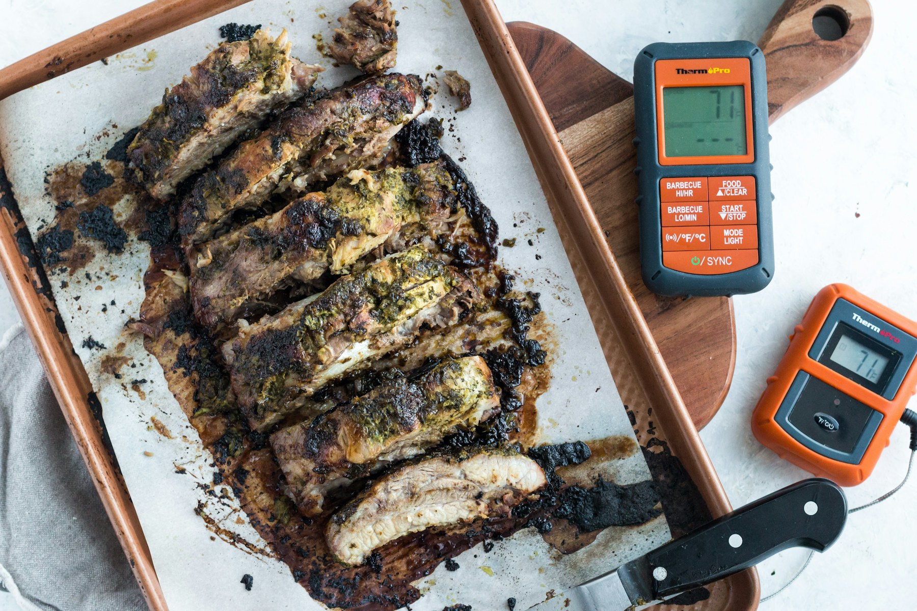 Digital thermometer beside cooked meat on a cutting board